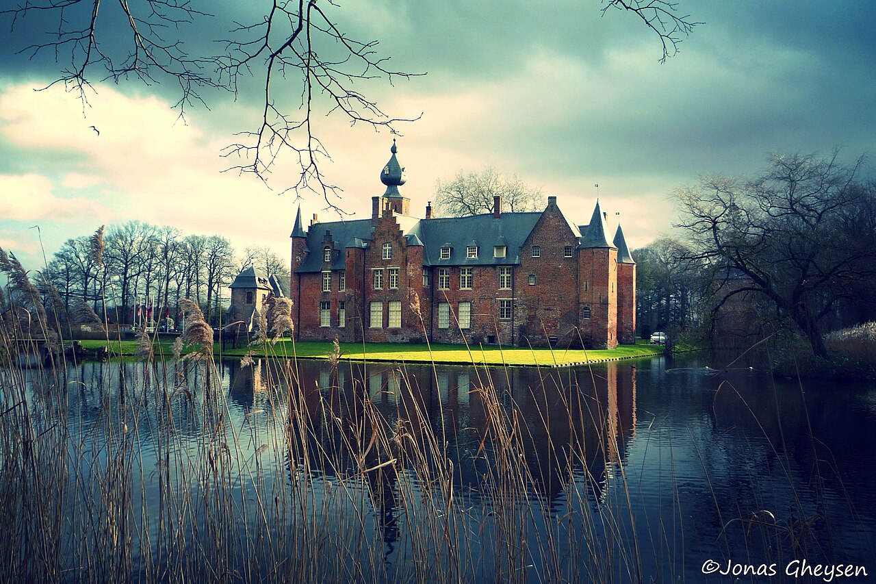 Kasteel van Rumbeke met bakstenen vleugels en torenspitsen weerspiegeld in het water, gefotografeerd in 2014